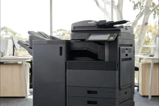 A large office multifunction copier standing in a bright open plan office