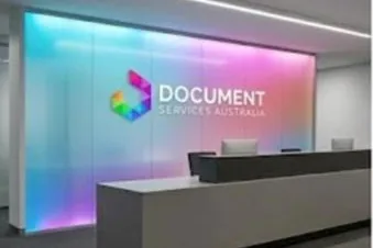A reception desk in front of a wall lit in the DSA brand colours, the Document Services Australia mark on it